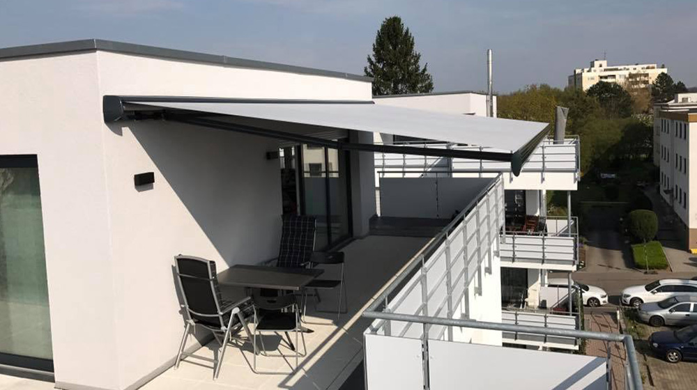 Gelenkarmmarkise spendet Schatten auf modernem Stadtbalkon