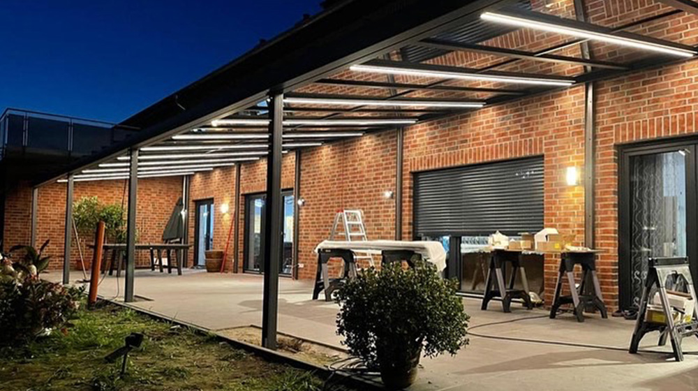 Modernes Terrassendach mit LED-Beleuchtung an einem Backsteinhaus bei Nacht