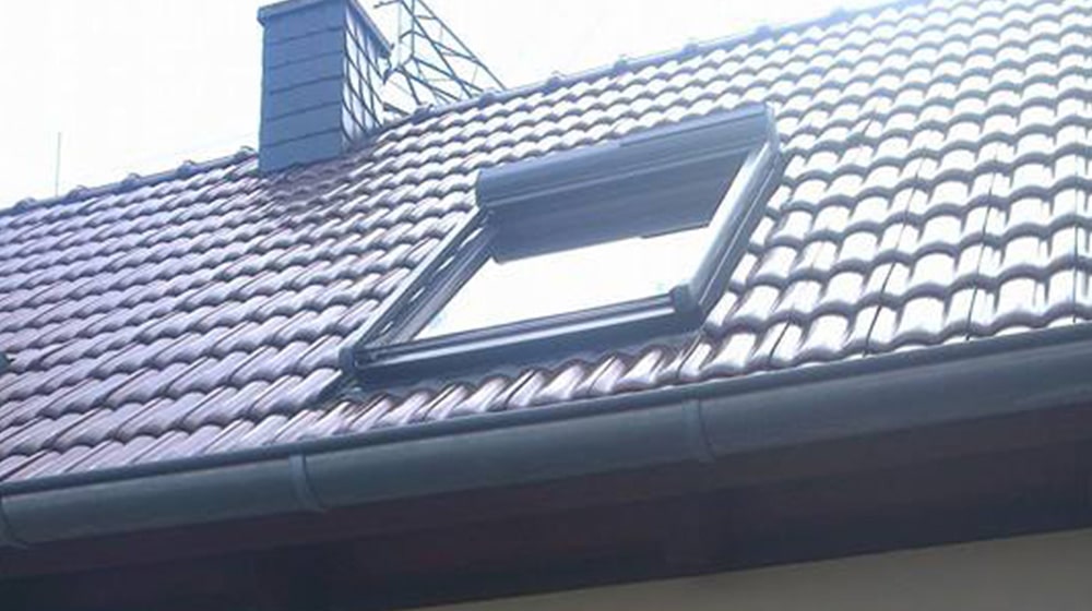 Modernes Dachfenster mit Rolladen – eingebaut auf Ziegeldach eines Wohnhauses