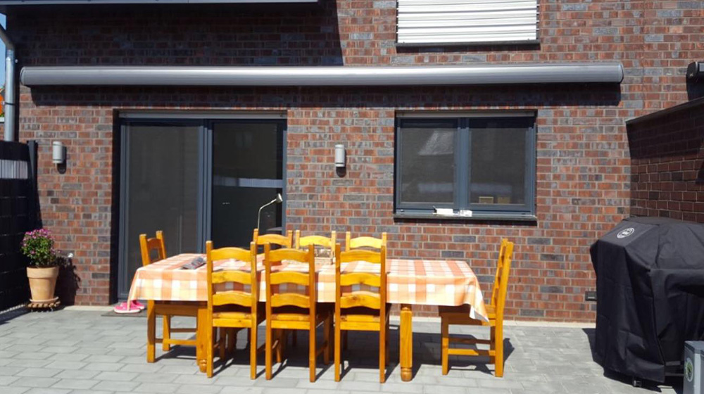 Geschlossene Gelenkarmmarkise an Backsteinfassade – vorbereitet für Sonnenschutz
