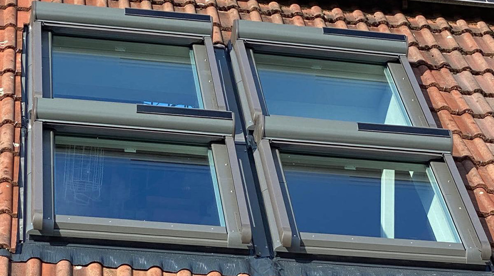 Moderne Dachfenster mit Wärmeschutz unter Solarpanelen auf Ziegeldach
