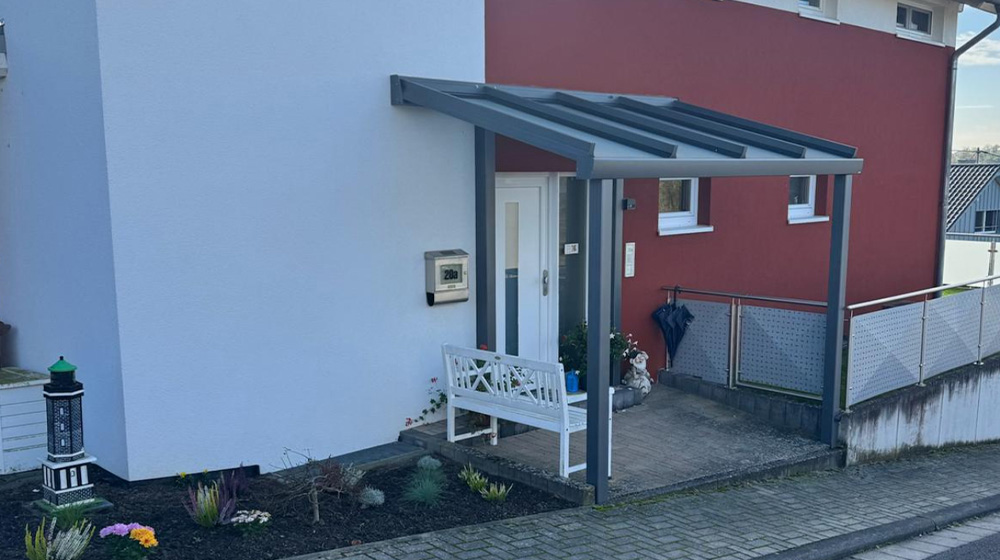 Eingangsbereich mit Glasvordach und moderner Haustür