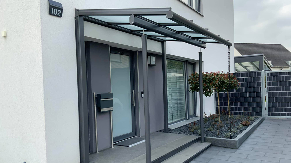Überdachter Hauseingang mit moderner Haustür und seitlicher Glaswand