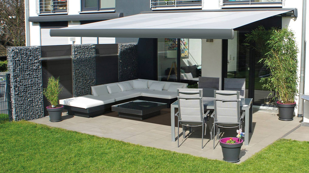 Ausgefahrene Gelenkarmmarkise über moderner Terrasse mit Sitz- und Essbereich