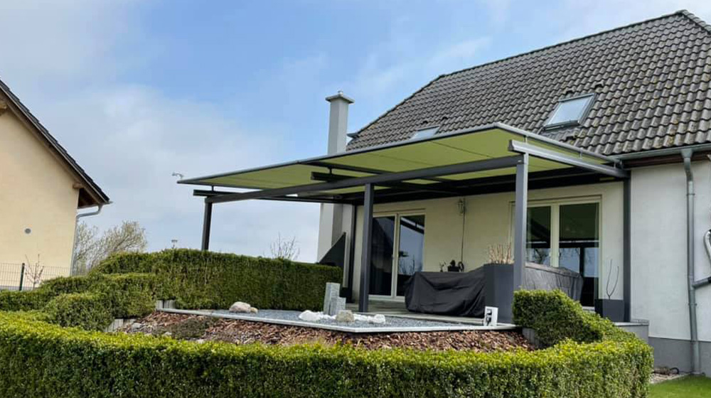 Grüne Pergola Markise mit großer Ausfalltiefe über Terrasse eines Einfamilienhauses