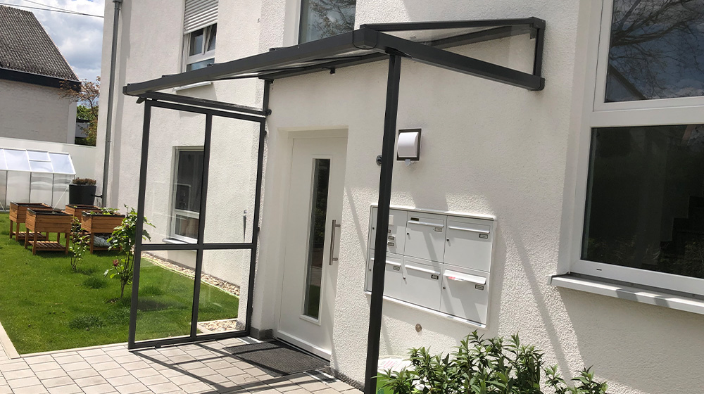 Überdachter Hauseingang mit Briefkastenanlage und Glas-Seitenschutz