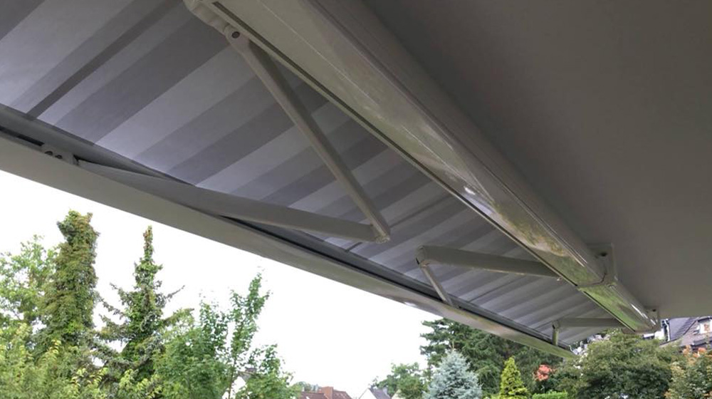 Ausgefahrene Gelenkarmmarkise über einer Terrasse mit Gartenblick