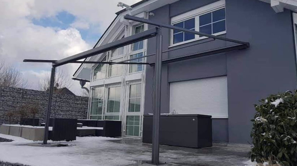 Pergola Markise im Aufbau auf verschneiter Terrasse eines modernen Hauses