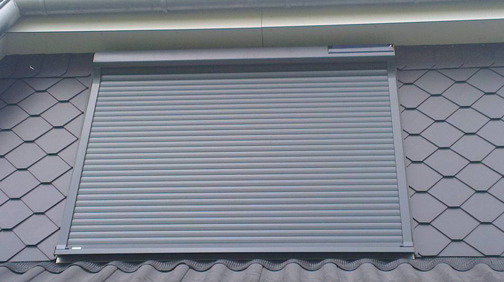 Dunkelgrauer Vorbaurollladen montiert am Dachfenster für Wärmeschutz