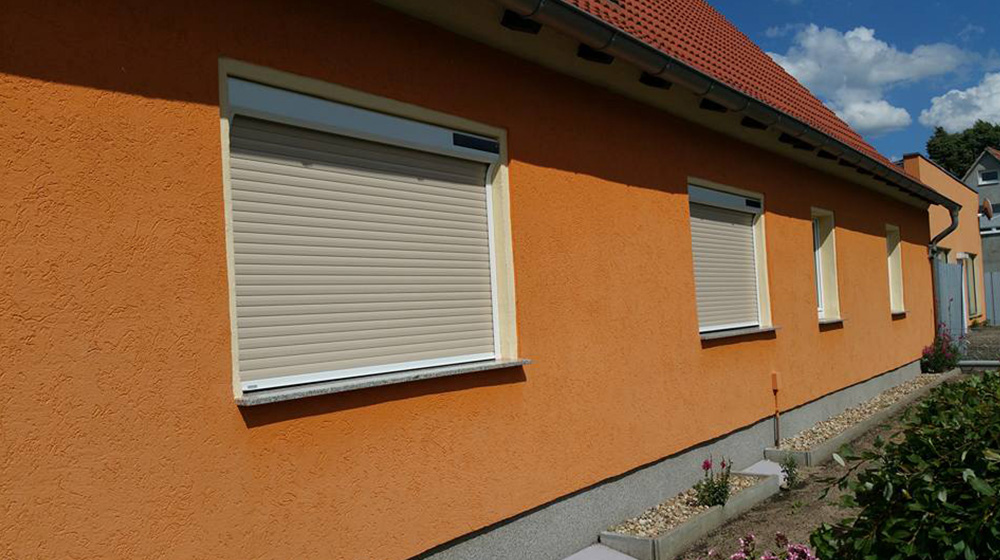 Vorbaurollläden an orangefarbener Hausfassade montiert