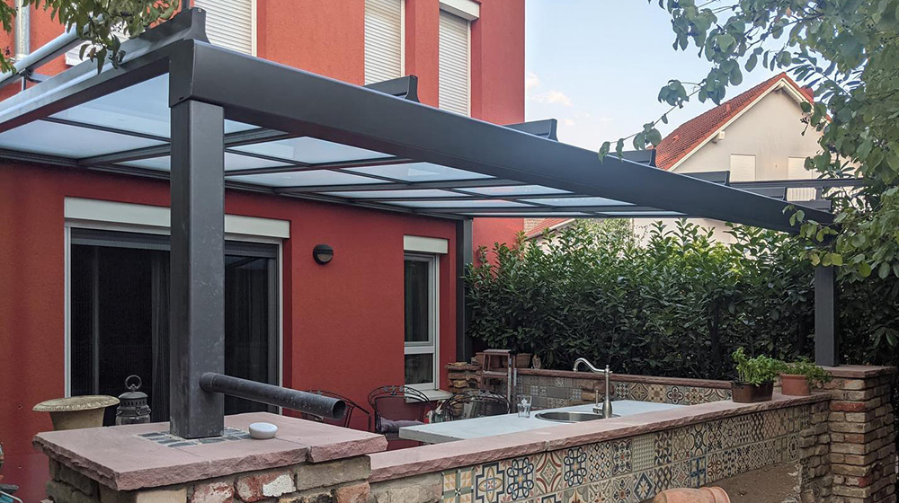 Modernes Terrassendach aus Glas über einer gemauerten Gartenküche mit Spüle