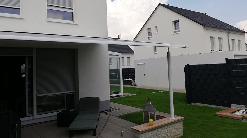 Weiße Pergola-Markise an moderner Hausfassade mit Gartenmöbeln