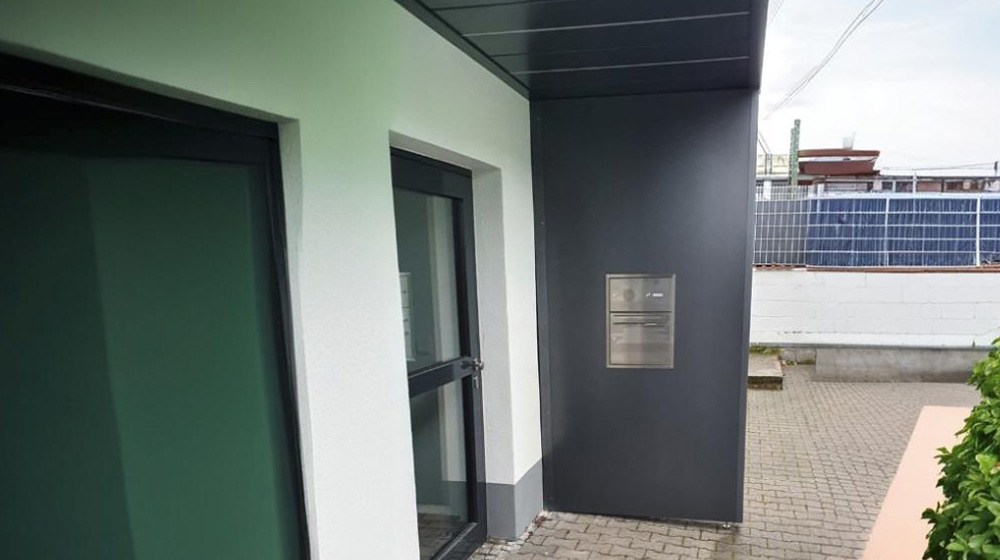 Moderner Hauseingang mit dunklem Fassadenelement und Edelstahl-Briefkasten